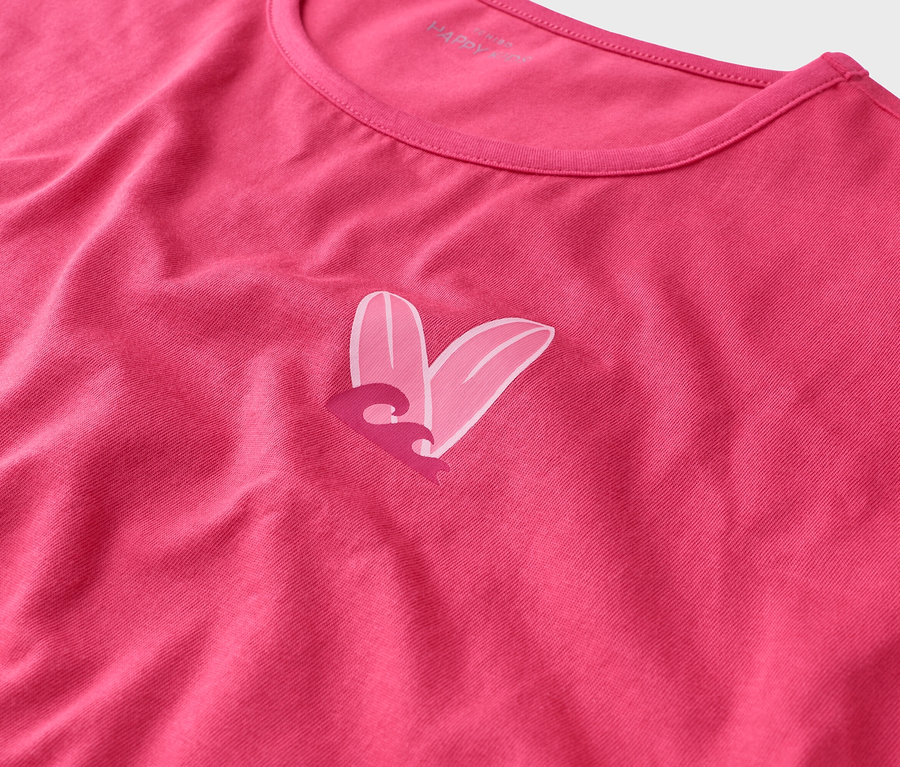 Detailní záběr na růžové tričko s designem srdce vytvořeným ze dvou surfových prken a vlny.