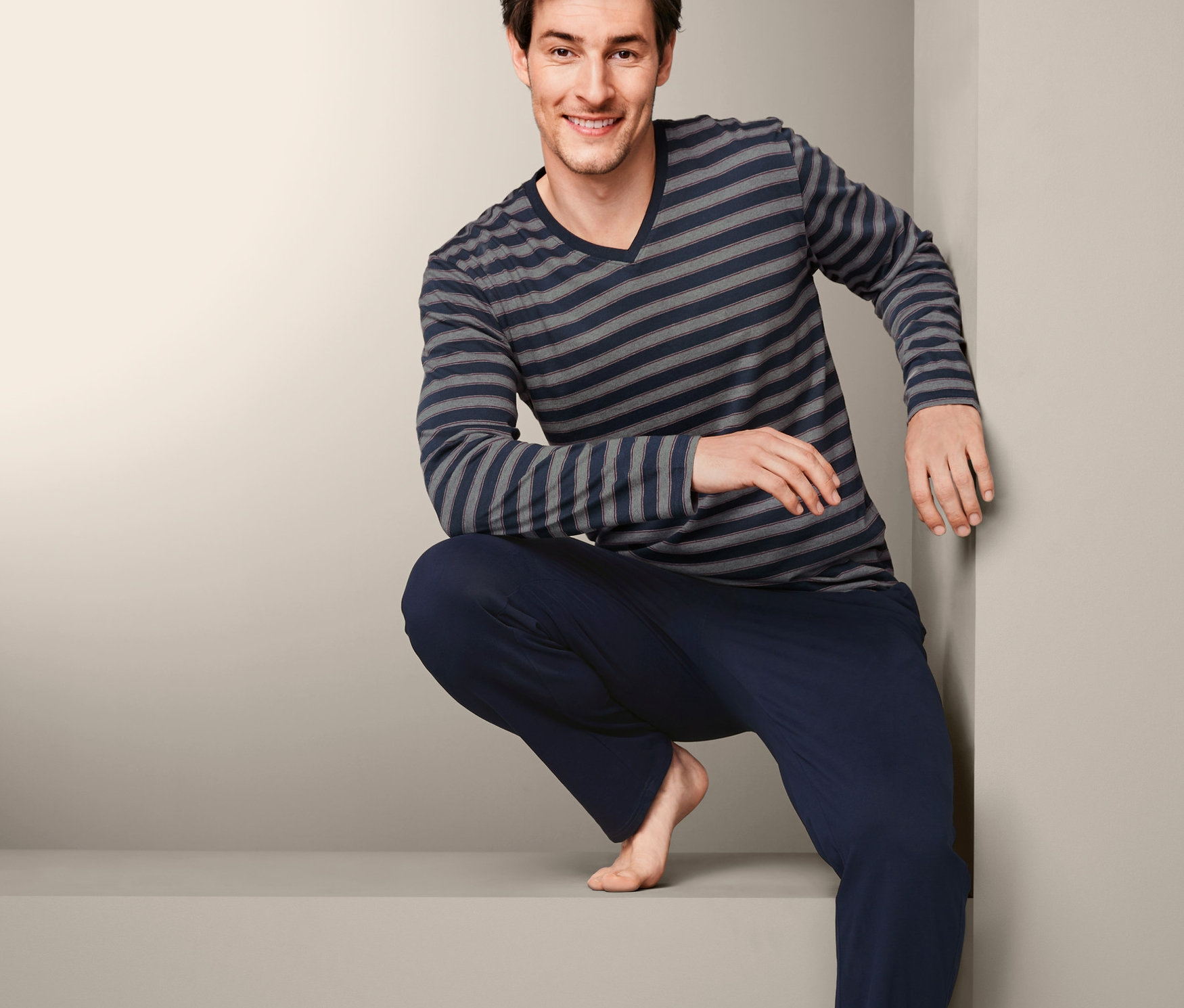Muž v pyžamu s dlouhým rukávem a pruhovaným topem.