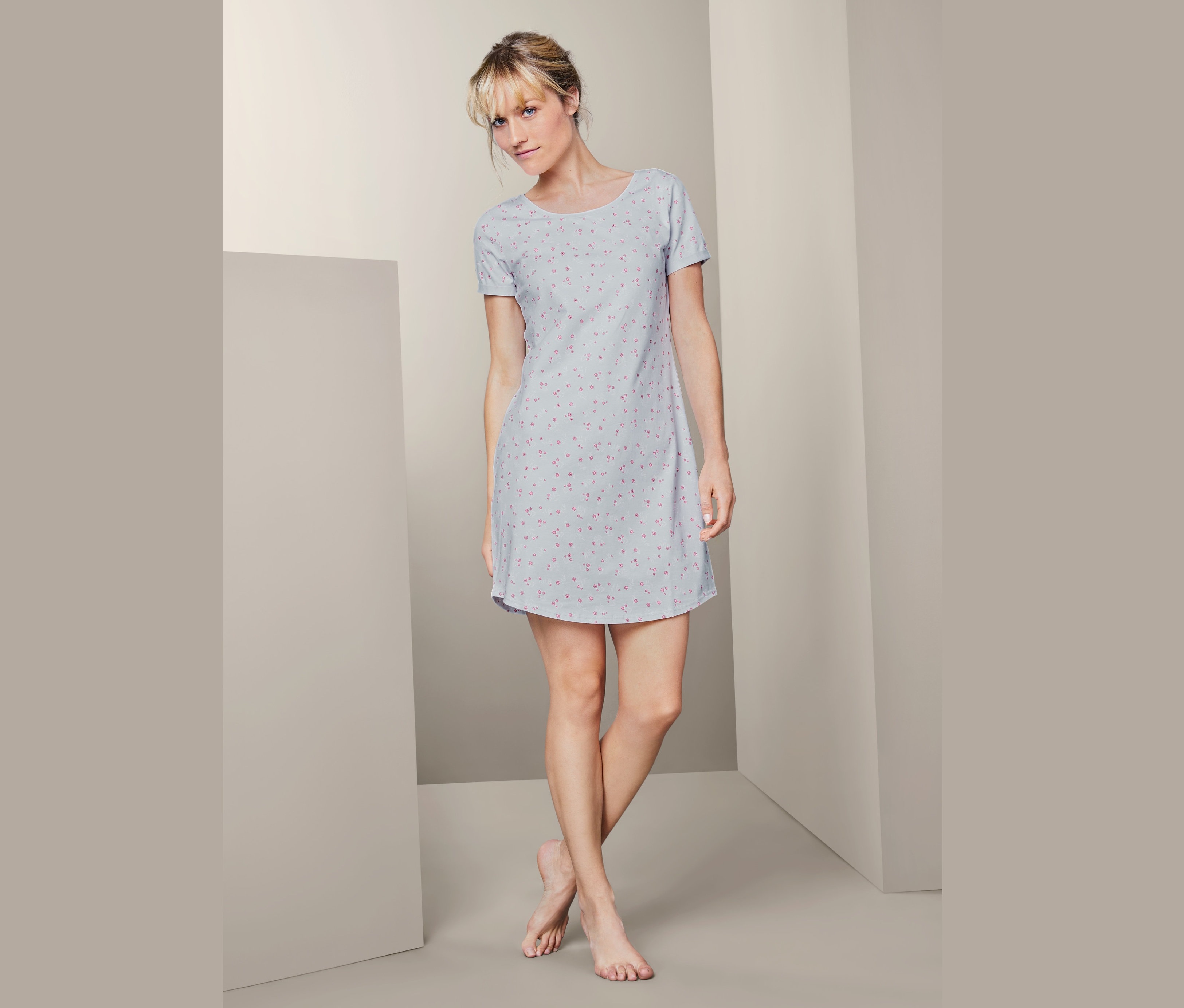 Žena stojí a má na sobě noční košili s krátkým rukávem.