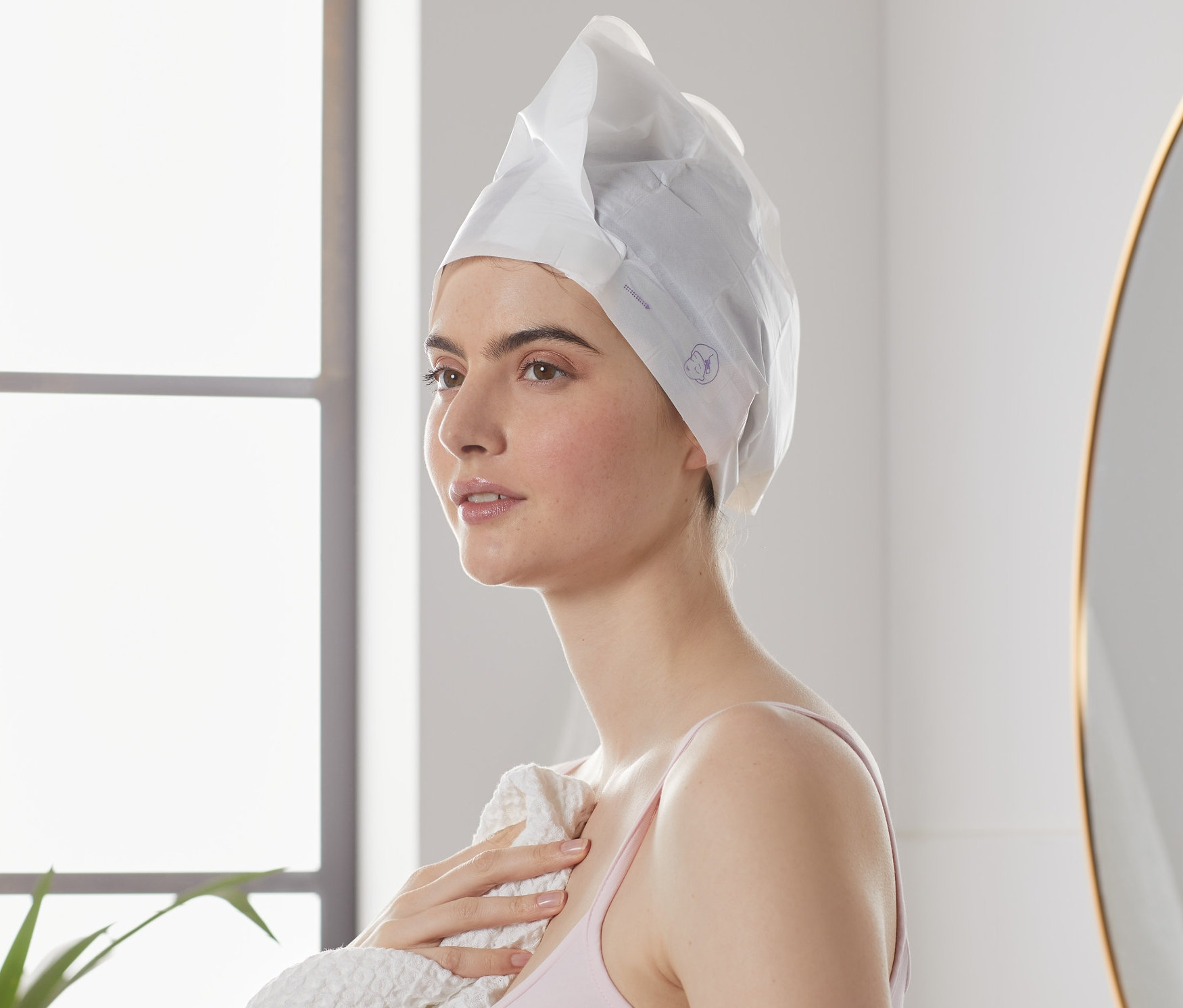 Žena s hřejivou maskou na vlasy (2 ks) a ručníkem v koupelně.