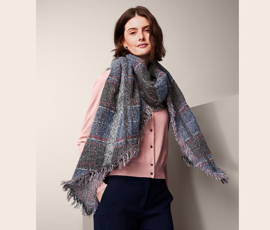 Žena má na sobě tkanou šálu XXL.