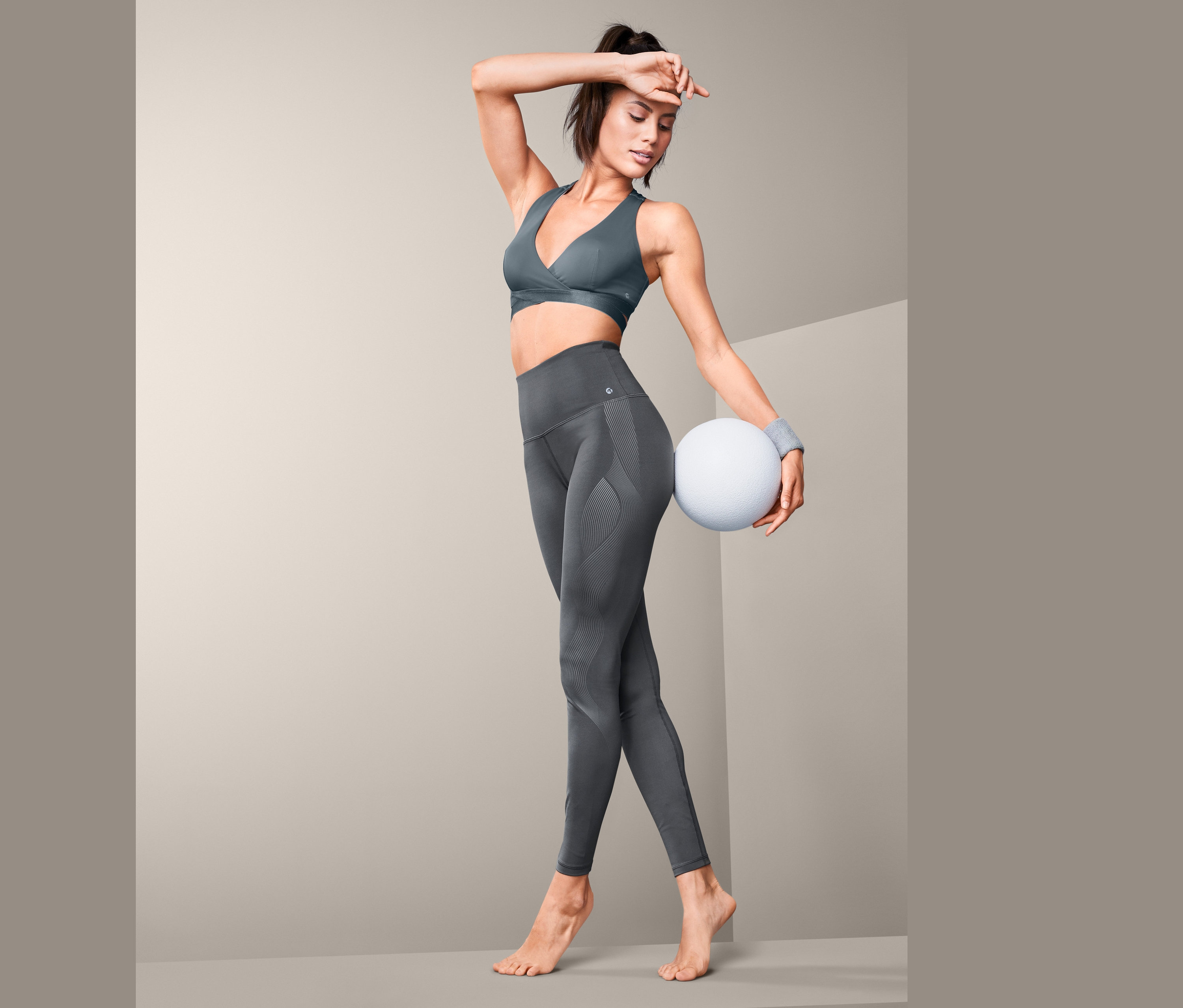 Žena pózuje ve sportovní podprsence a stahovacích sportovních legínách.