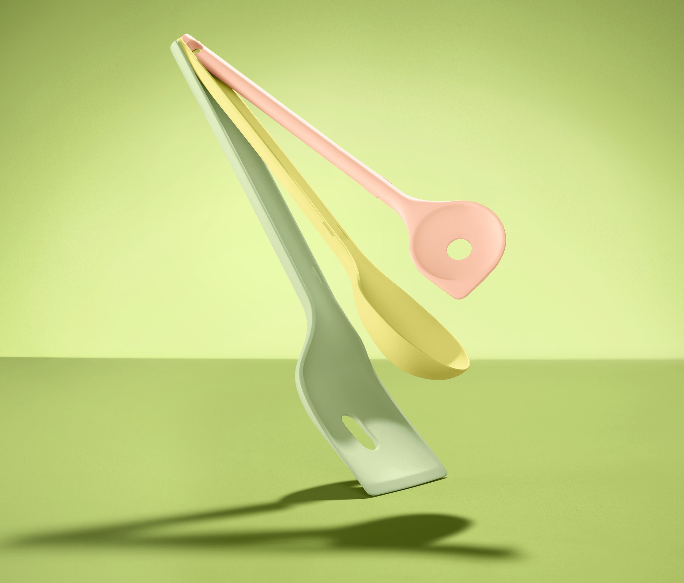 Na zeleném pozadí levitují tři kuchyňské pomůcky, 3 ks.