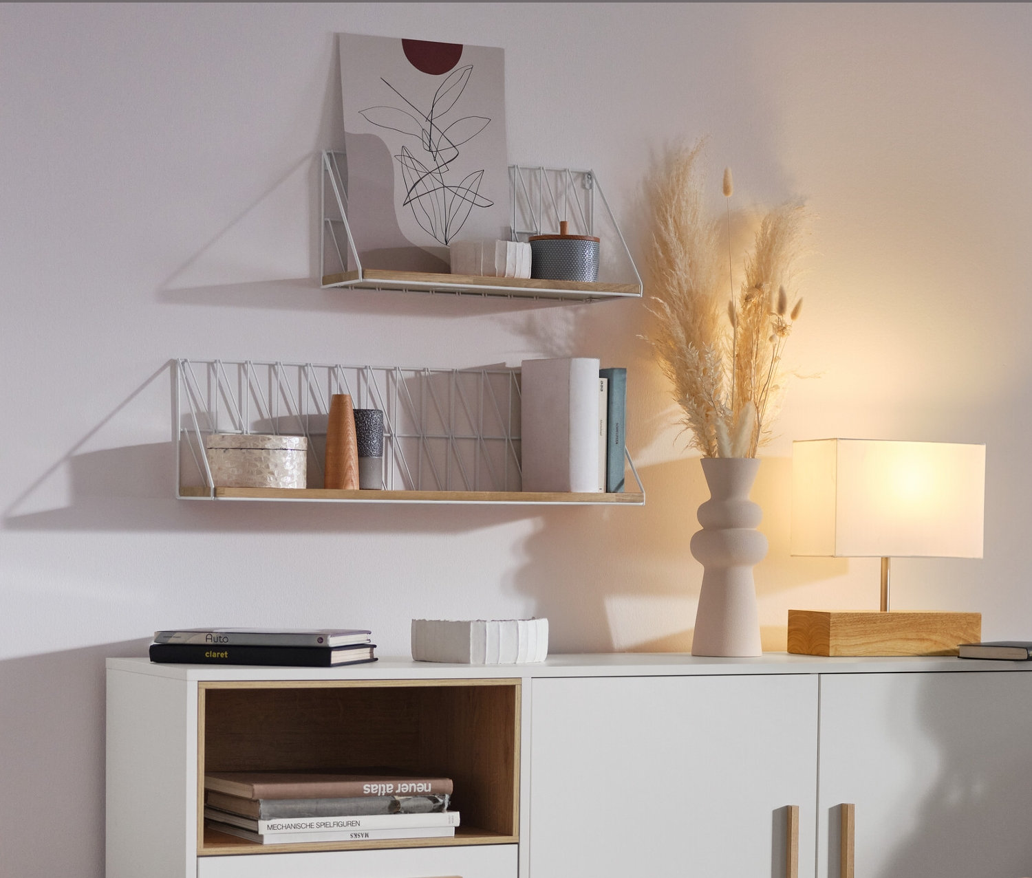 Žena sedí v obývacím pokoji vedle bílé odkládací skříňky »Eklund« se zásuvkami a dvířky.