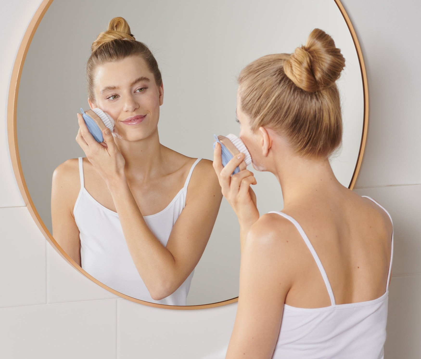 Žena používá kartáček na čištění obličeje.