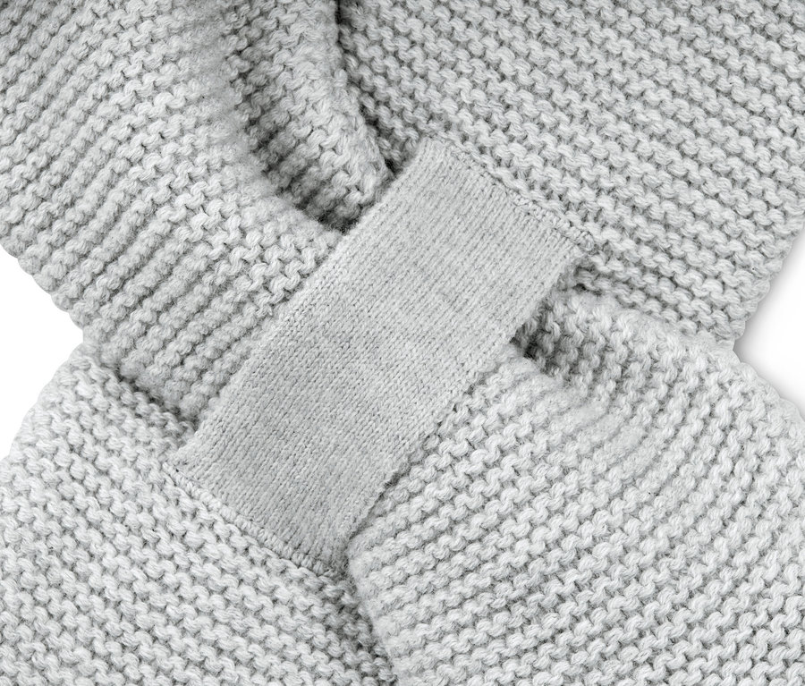 Detailní záběr pletené šály a čepice světle šedé barvy.