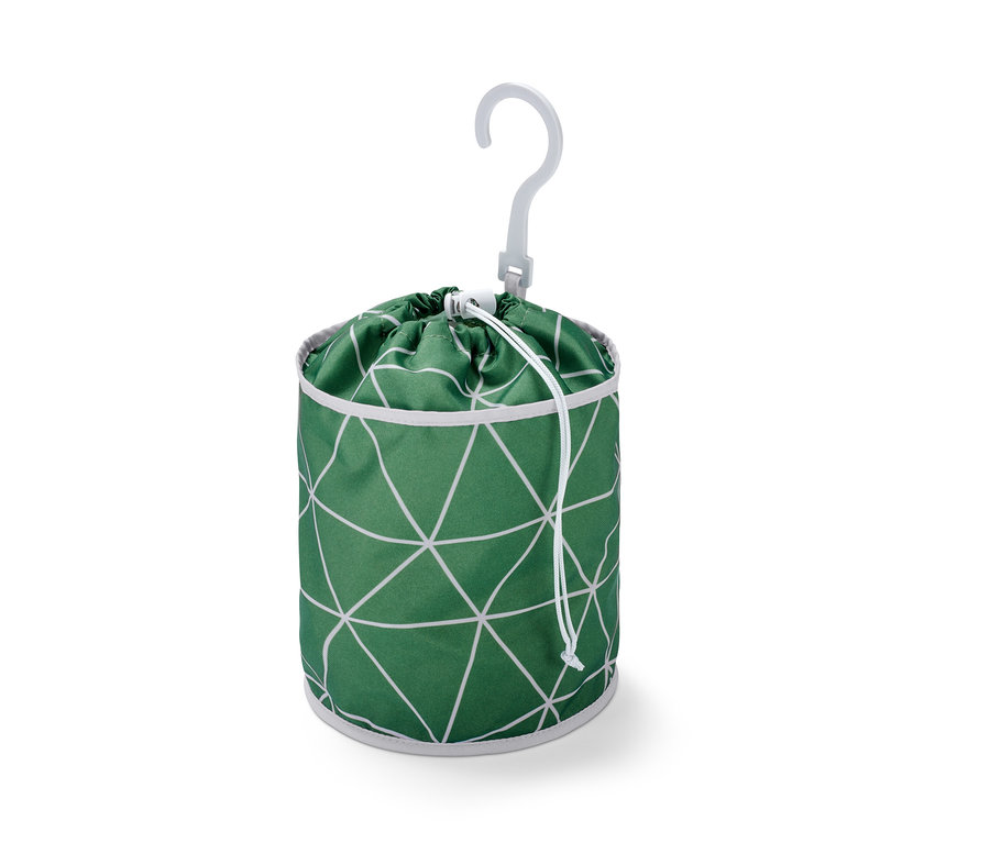 Zelený sáček na kolíčky na prádlo se vzorem bílých trojúhelníků a bílým plastovým věšákem.