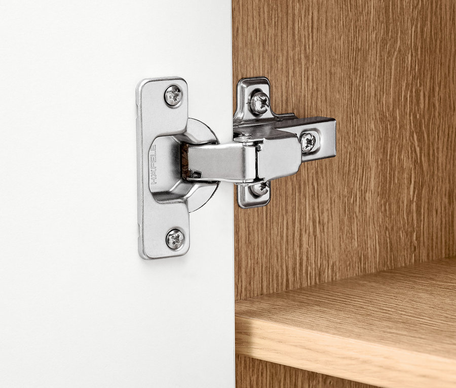 Detail stříbrného pantu na bílé skříňce Bekeson.