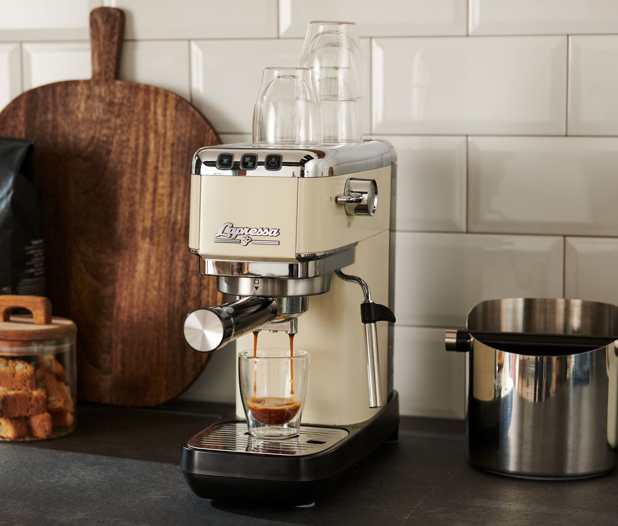 Krémově bílý pákový kávovar »Lapressa« připravuje espresso do sklenice.