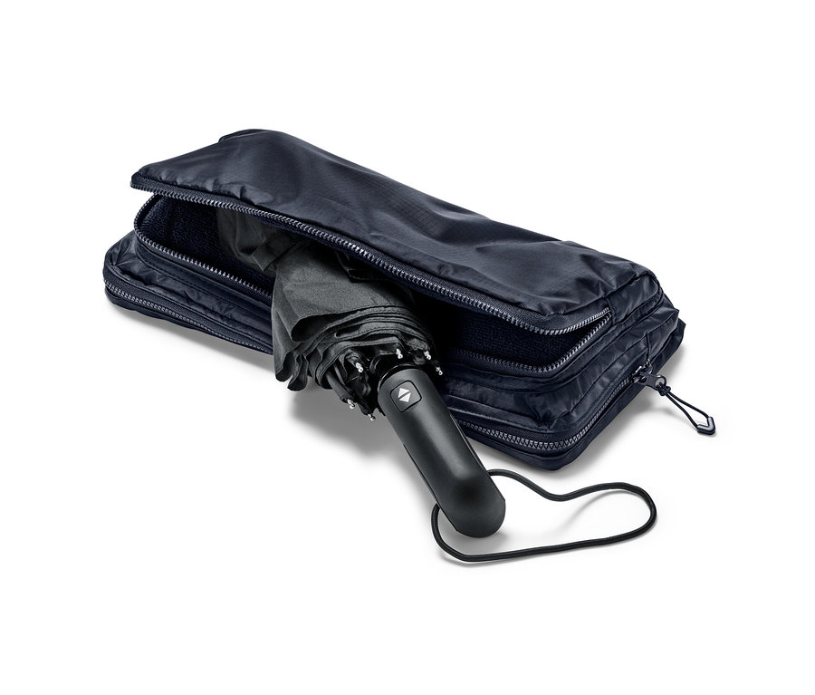 Černý deštník částečně zasunutý do modré nákupní tašky a batohu 2 v 1.