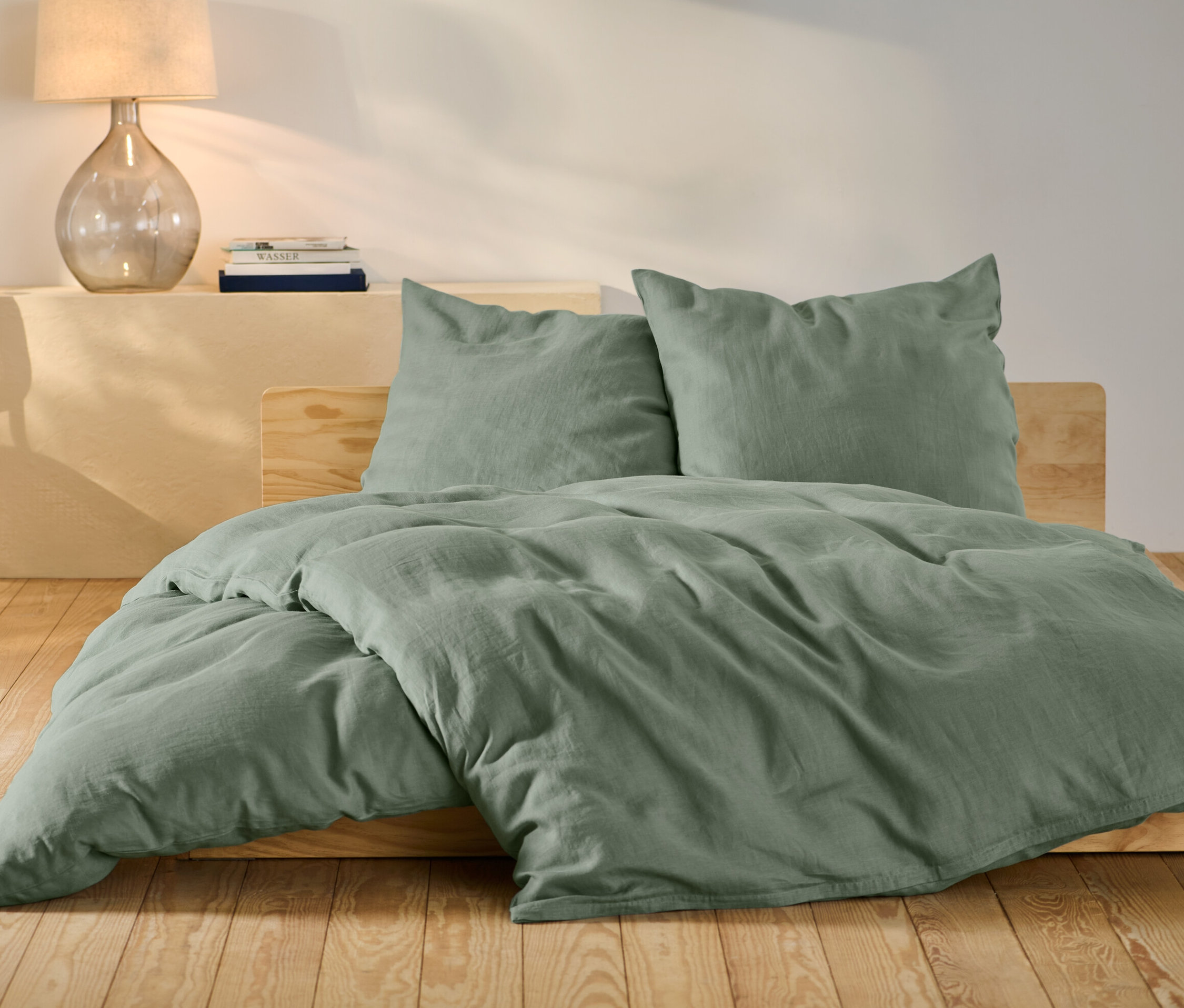 Zelené lněné povlečení standardní a nadměrné velikosti na posteli.