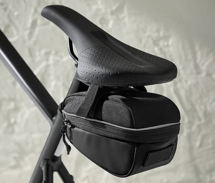 Černá cyklistická brašna pod sedlem připevněná k sedlu kola.
