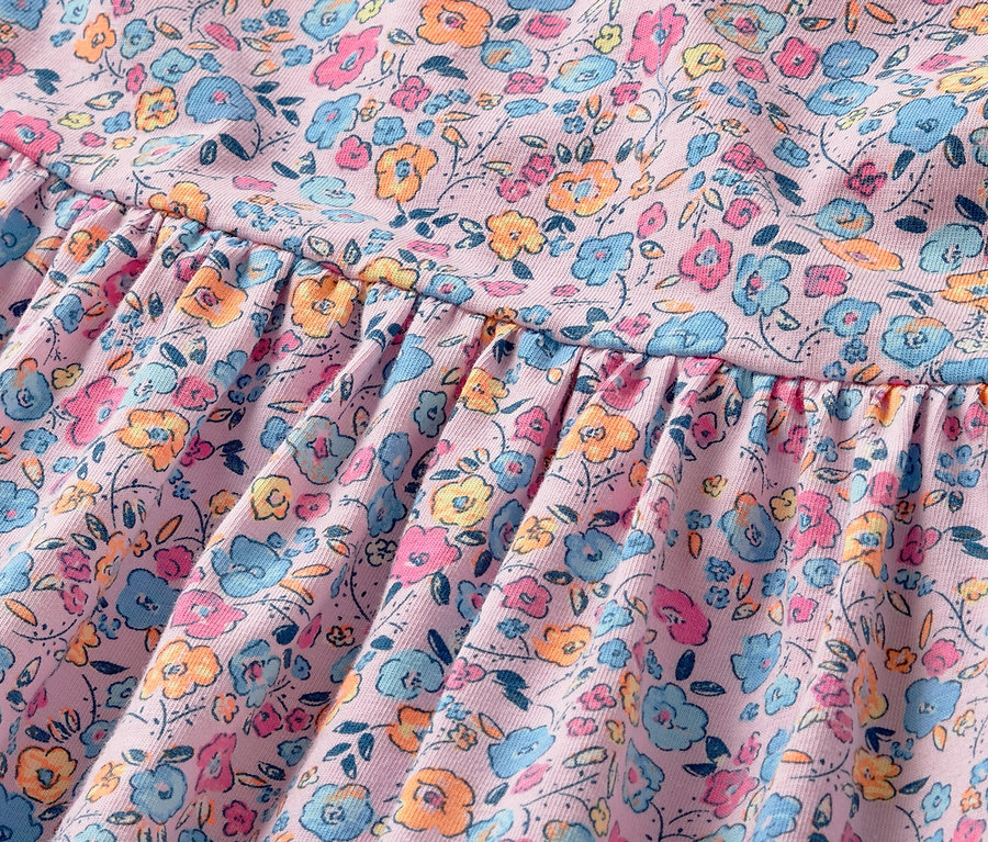 Detail dívčích žerzejových šatů s květinovým vzorem.