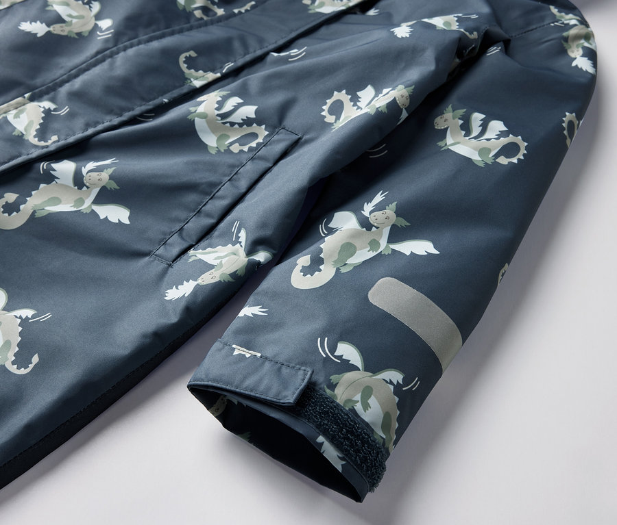 Detail dětské kombinézy do deště s motivem rytíře, s kapsou a reflexním prvkem.