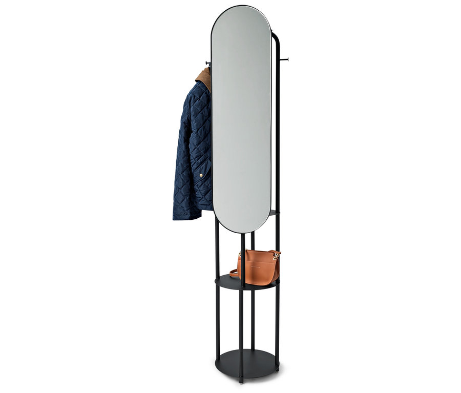 Černý stojan s oválným zrcadlem, modrá bunda a hnědá kabelka.
