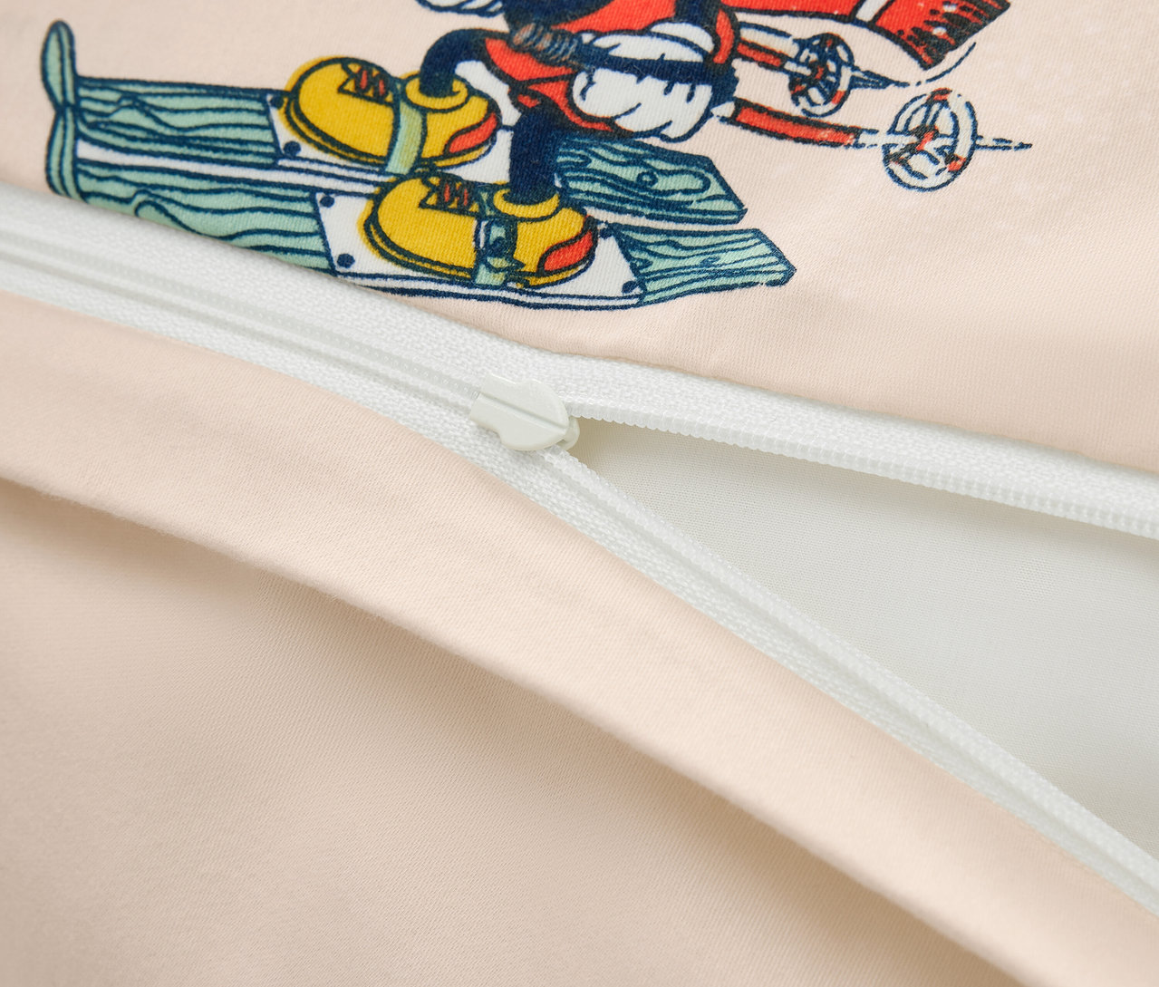 Detailní záběr na povlečení s potiskem Mickey Mouse na lyžích a částečně rozepnutým zipem.