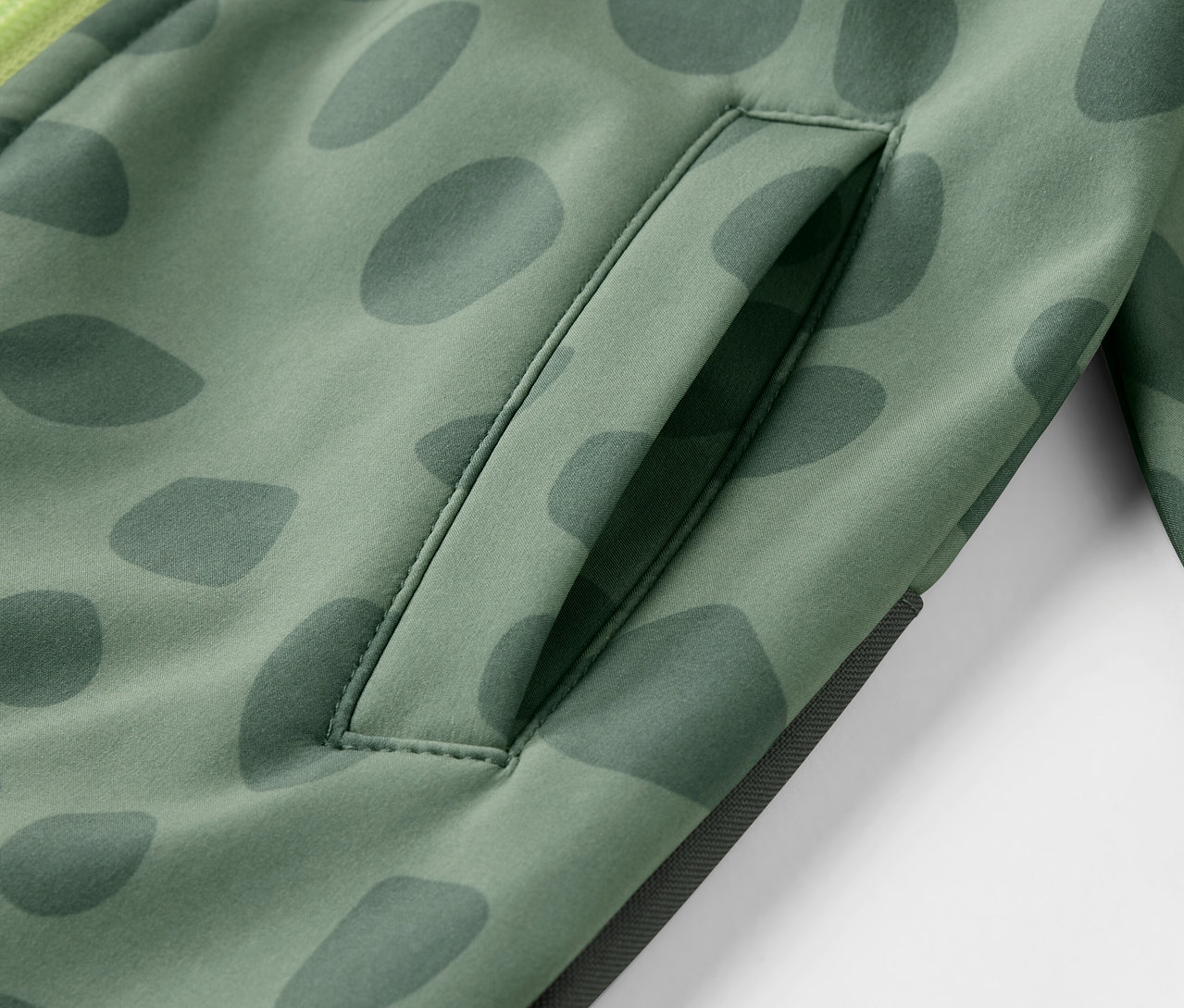 Detail dětské softshellové kombinézy se vzorem a kapsou.