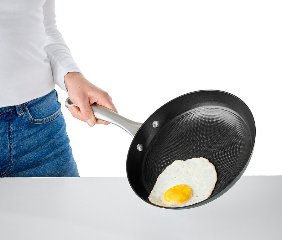 Žena drží pánev s smaženým vejcem.