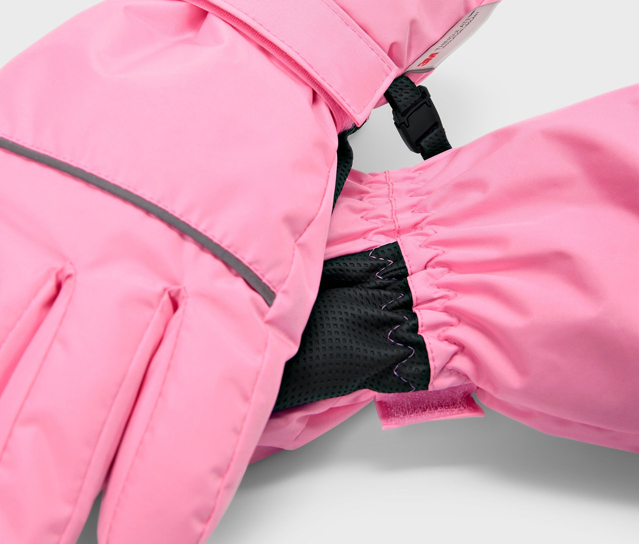 Detail růžových dětských lyžařských rukavic s černou vnitřní manžetou.