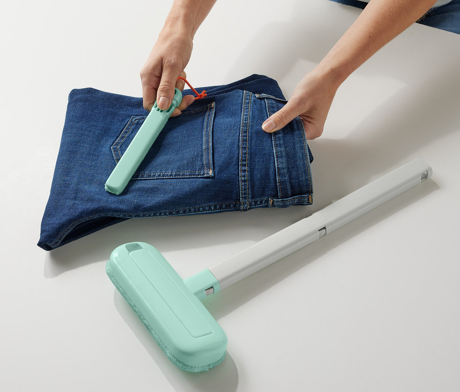 Osoba používá kartáč na čištění textilií 4 v 1 na složené džíny.