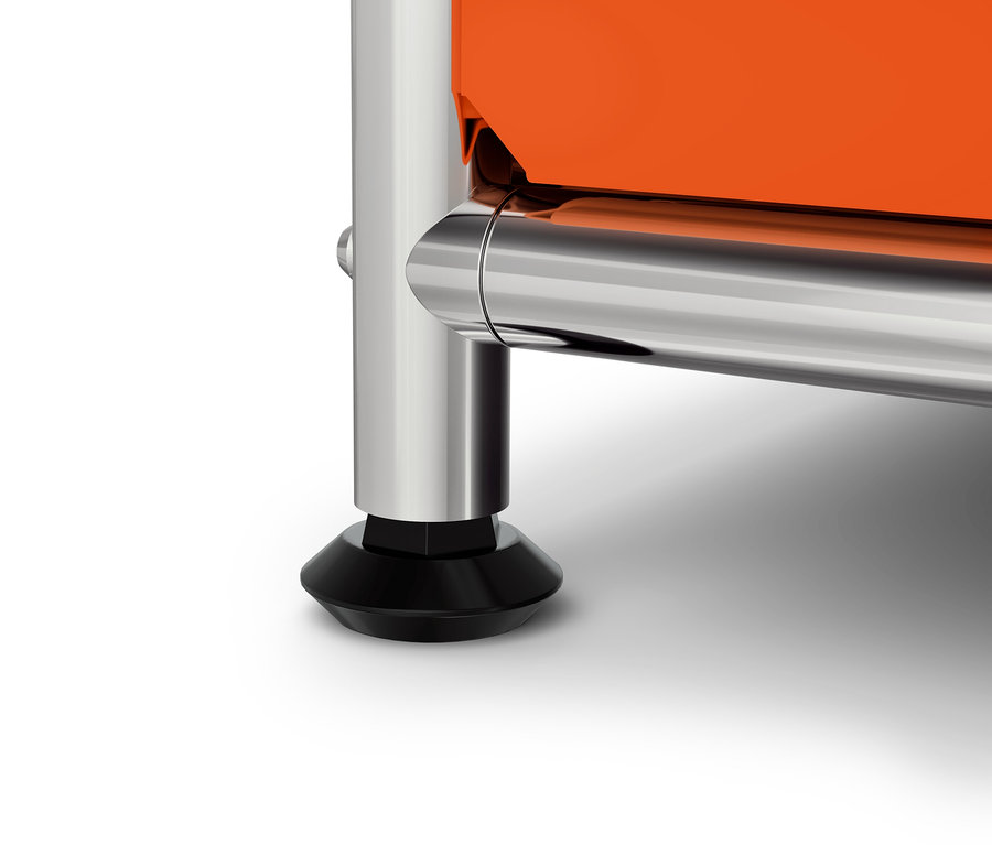 Detail oranžové skříňky s chromovanou nohou a černou patkou.