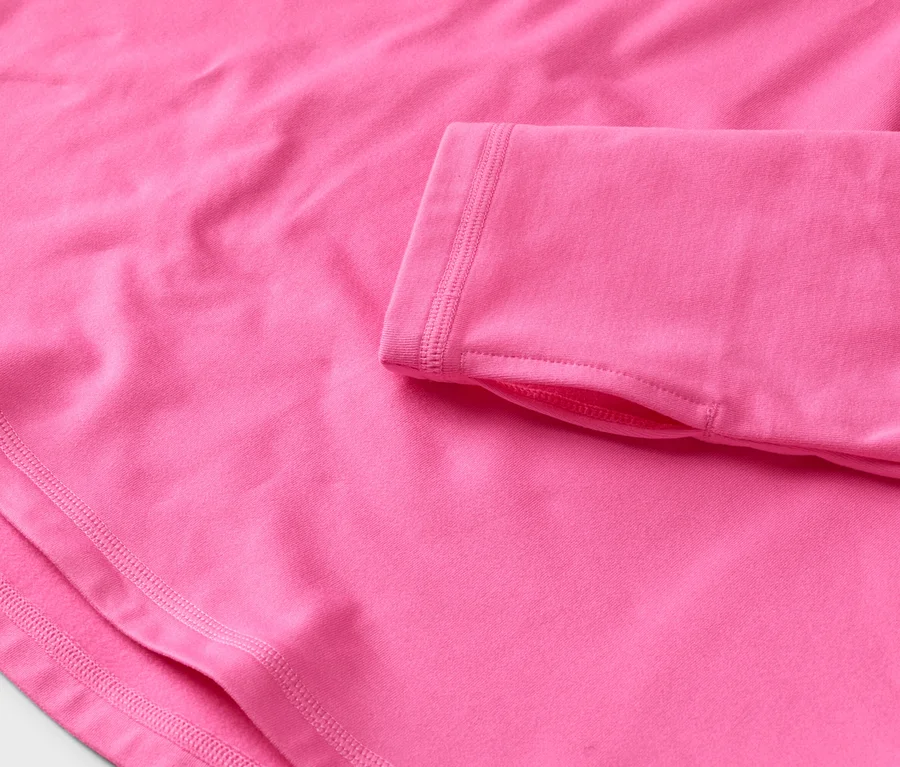 Detail růžového trička s dlouhým rukávem a otvory pro palce.
