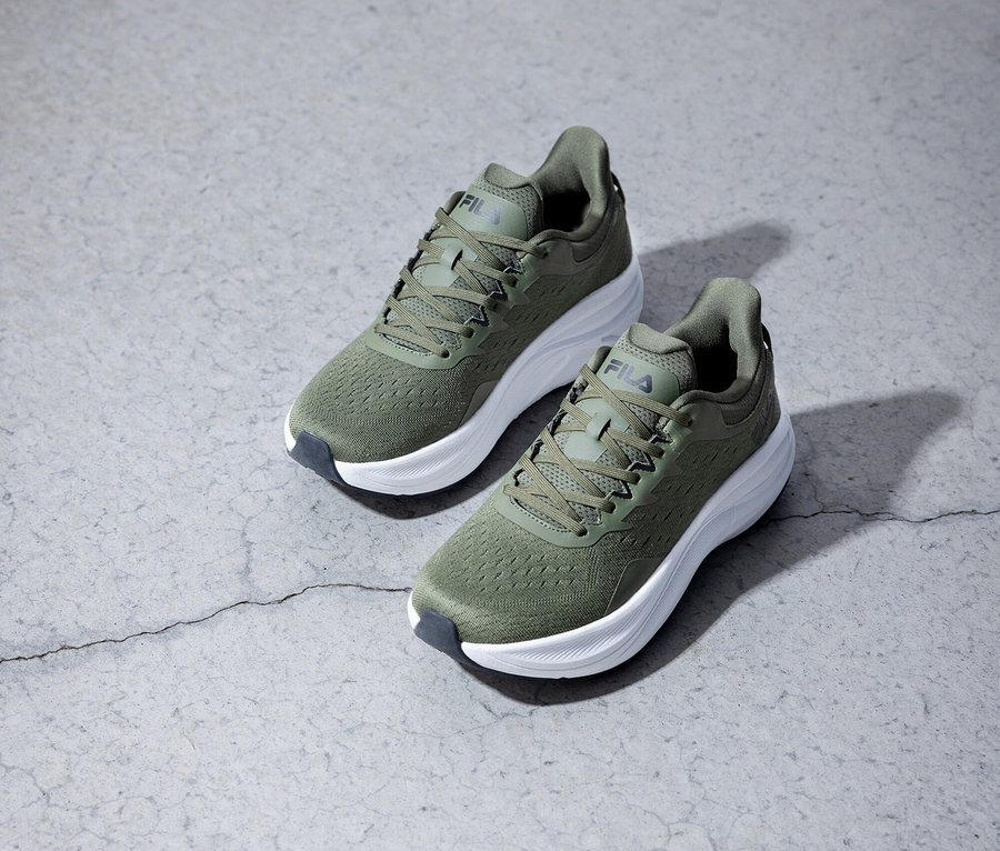 Dvě olivově zelené běžecké boty Fila stojí na šedém pozadí.