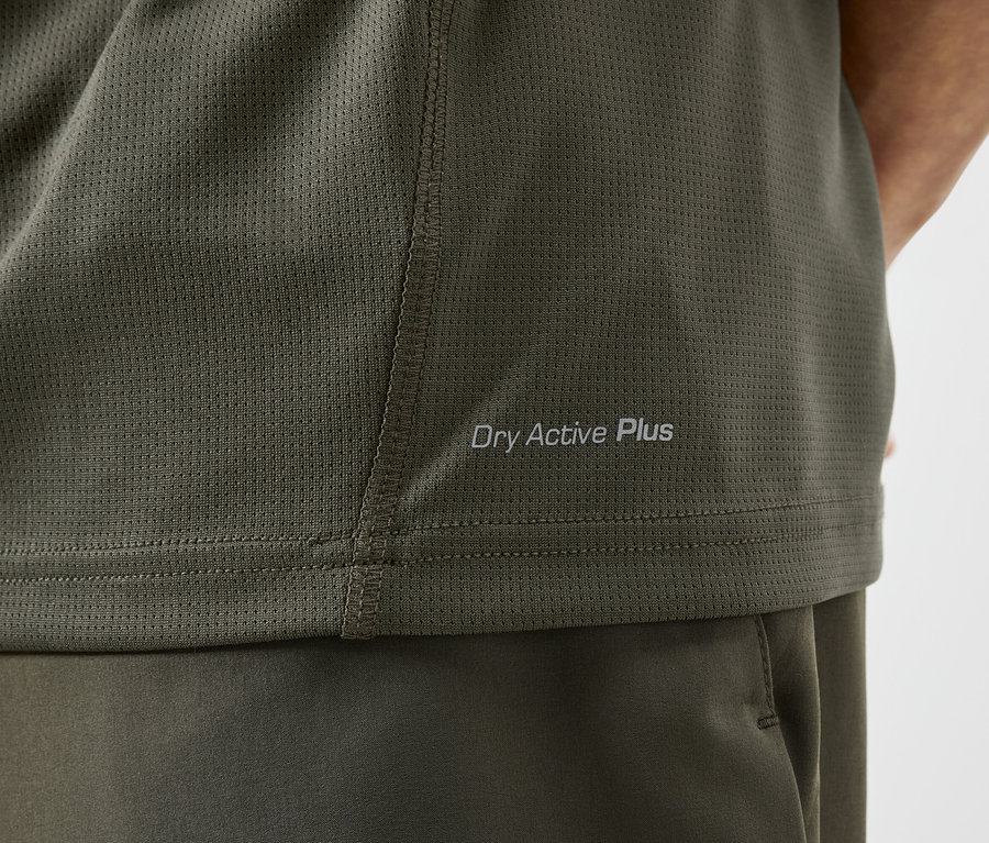 Detail olivového sportovního trička s nápisem "Dry Active Plus".