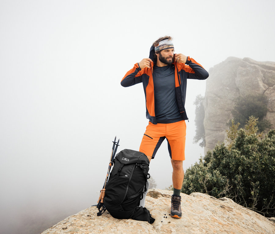 Muž stojí na skále s trekovým batohem CMP HAVRE, 40 litrů. Trekové hole opřené o batoh.