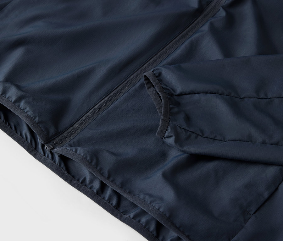 Detailní záběr tmavě modré bundy se zipem a kapsami.