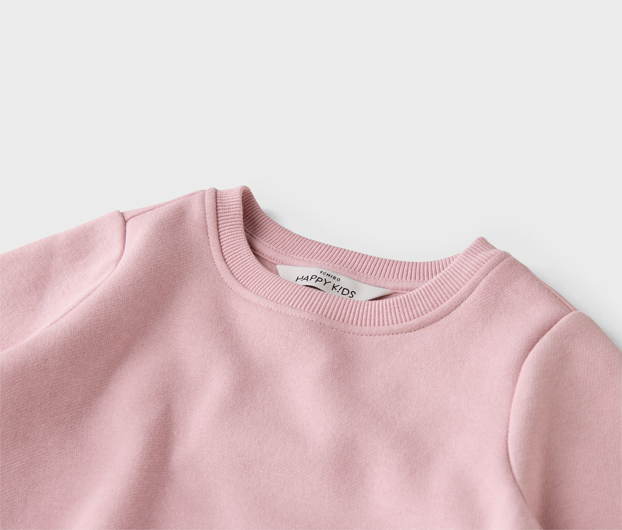 Detailní pohled na růžový svetr značky Tchibo Happy Kids s žebrovaným kulatým výstřihem.
