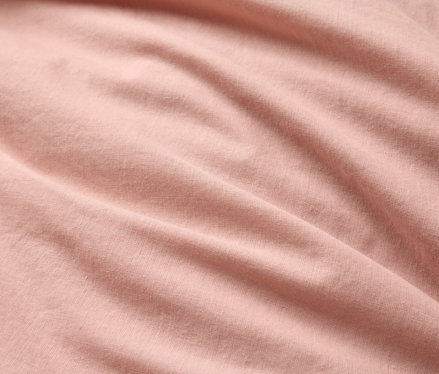 Detailní záběr zvlněné, světle růžové látky.
