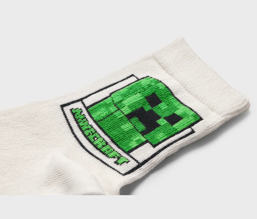 Detail bílé ponožky se zeleným motivem Minecraft Creeper.