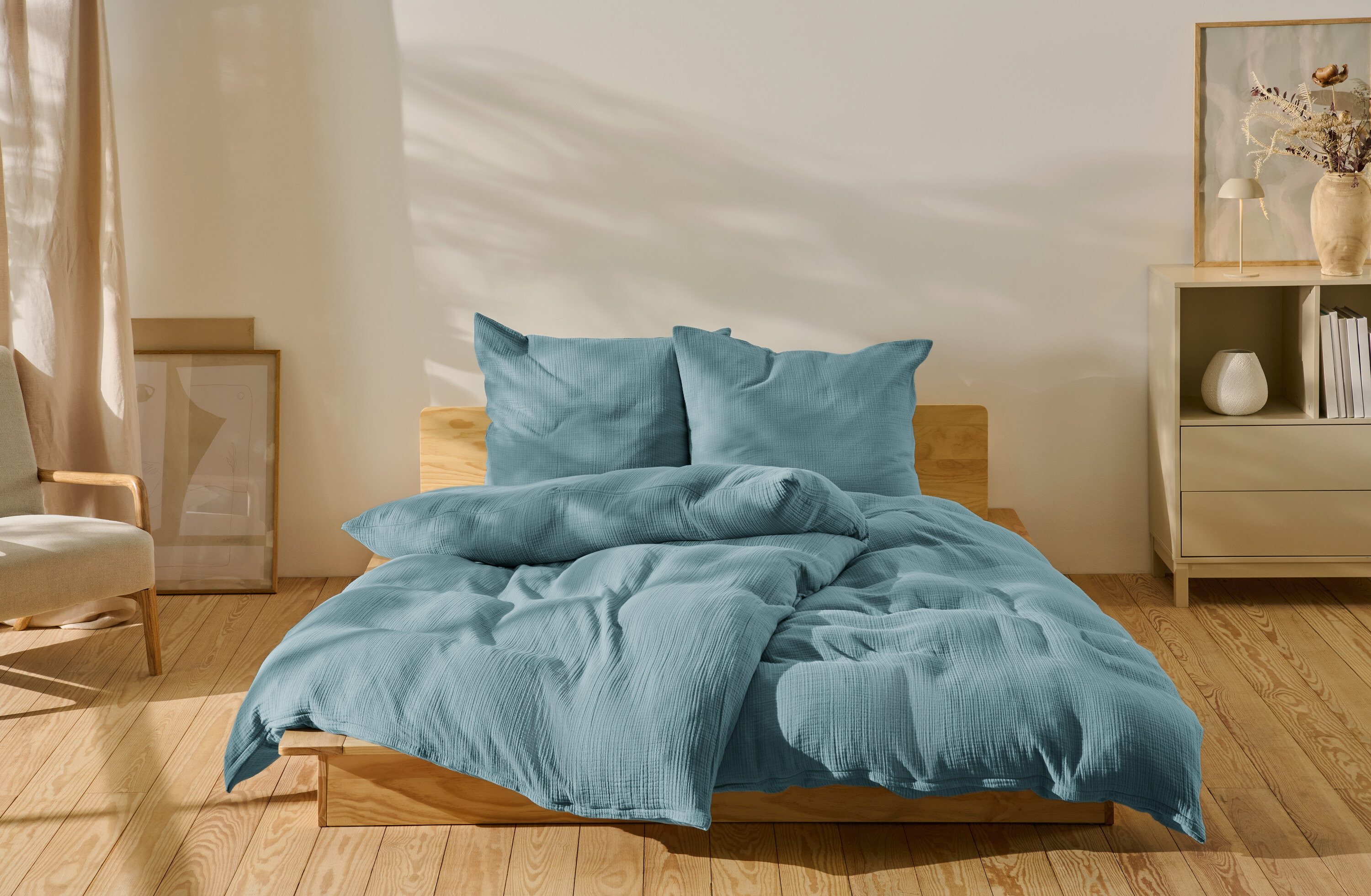 Modré mušelínové povlečení standardní velikosti a nadměrné velikosti na posteli.