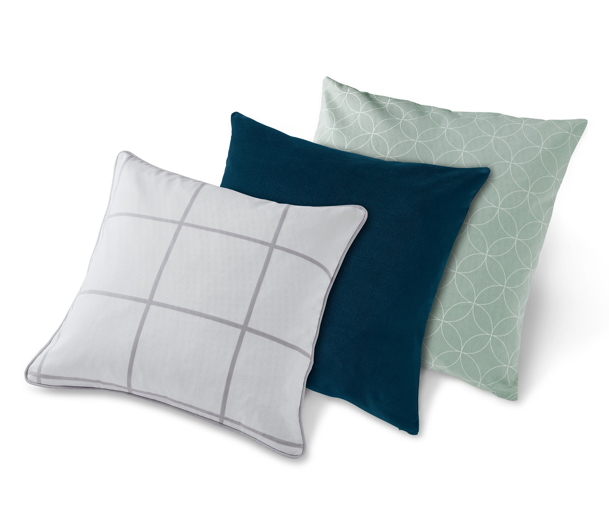 Tři dekorativní povlaky na polštáře: bílý s šedými čtverci, tmavě modrý a světle zelený s kruhy.
