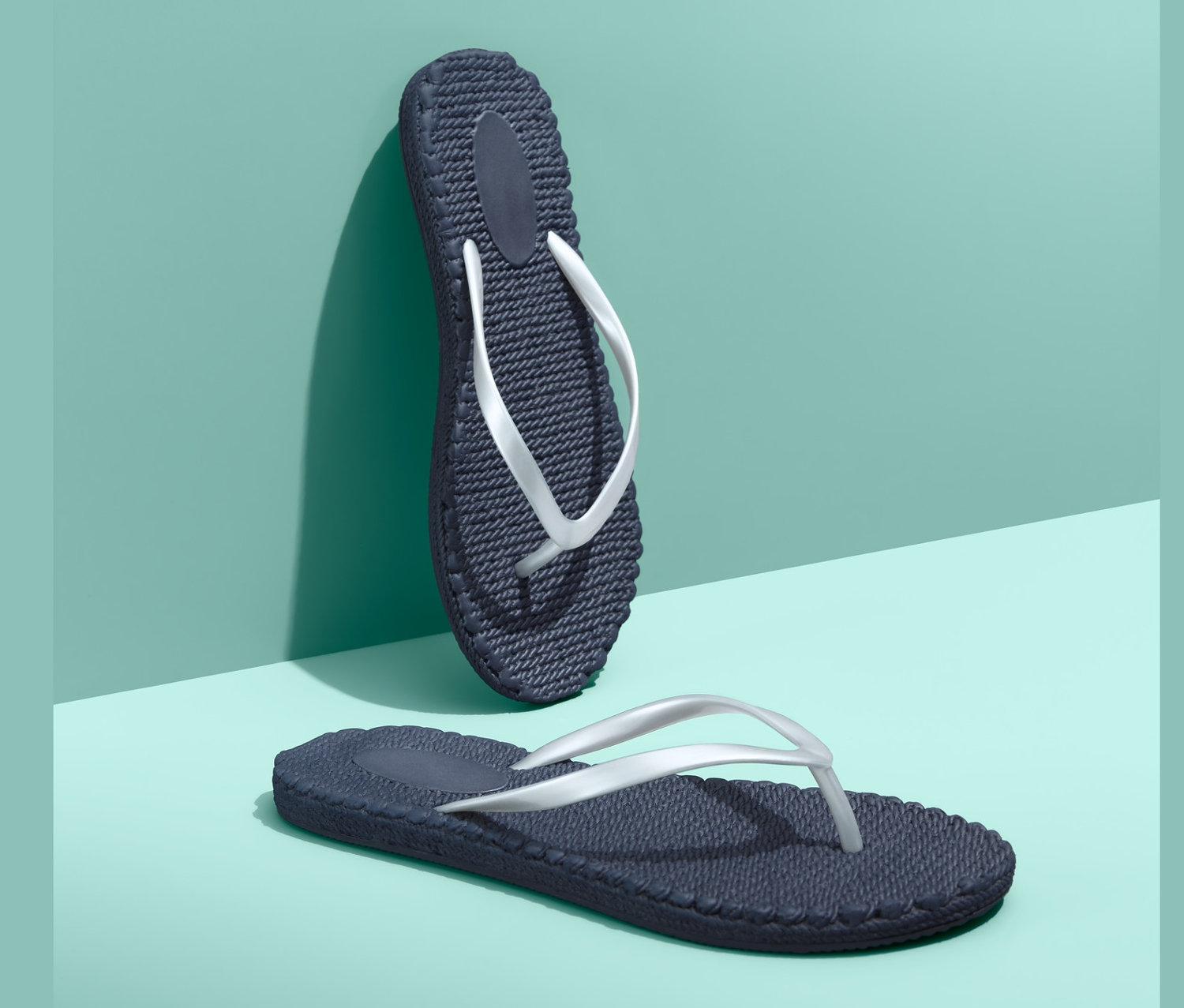 Dva tmavě modré žabky na tyrkysovém pozadí.