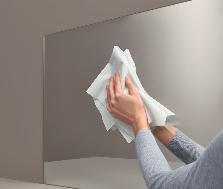 Žena čistí zrcadlo pomocí Speciálního čisticího hadříku.