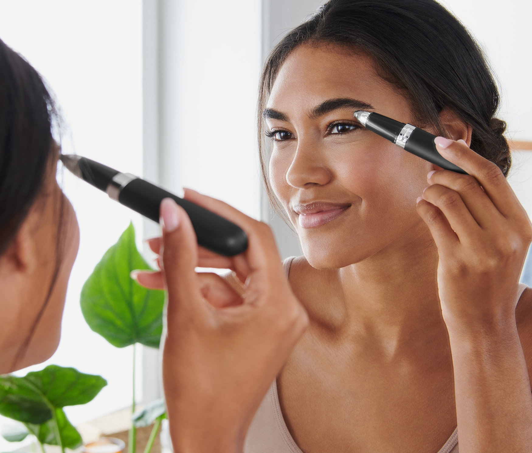 Žena si upravuje obočí elektrickým zastřihovačem obočí před zrcadlem.