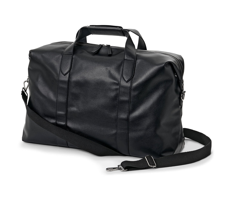 Černá cestovní taška s popruhem přes rameno leží na bílém pozadí.