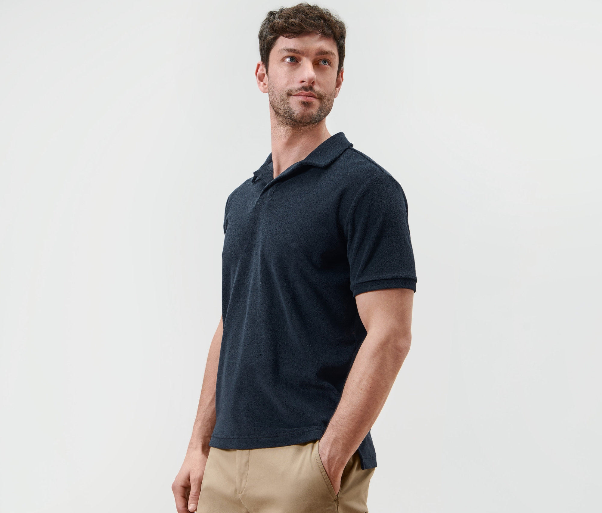 Muž pózuje v námořnické modré froté polokošili.