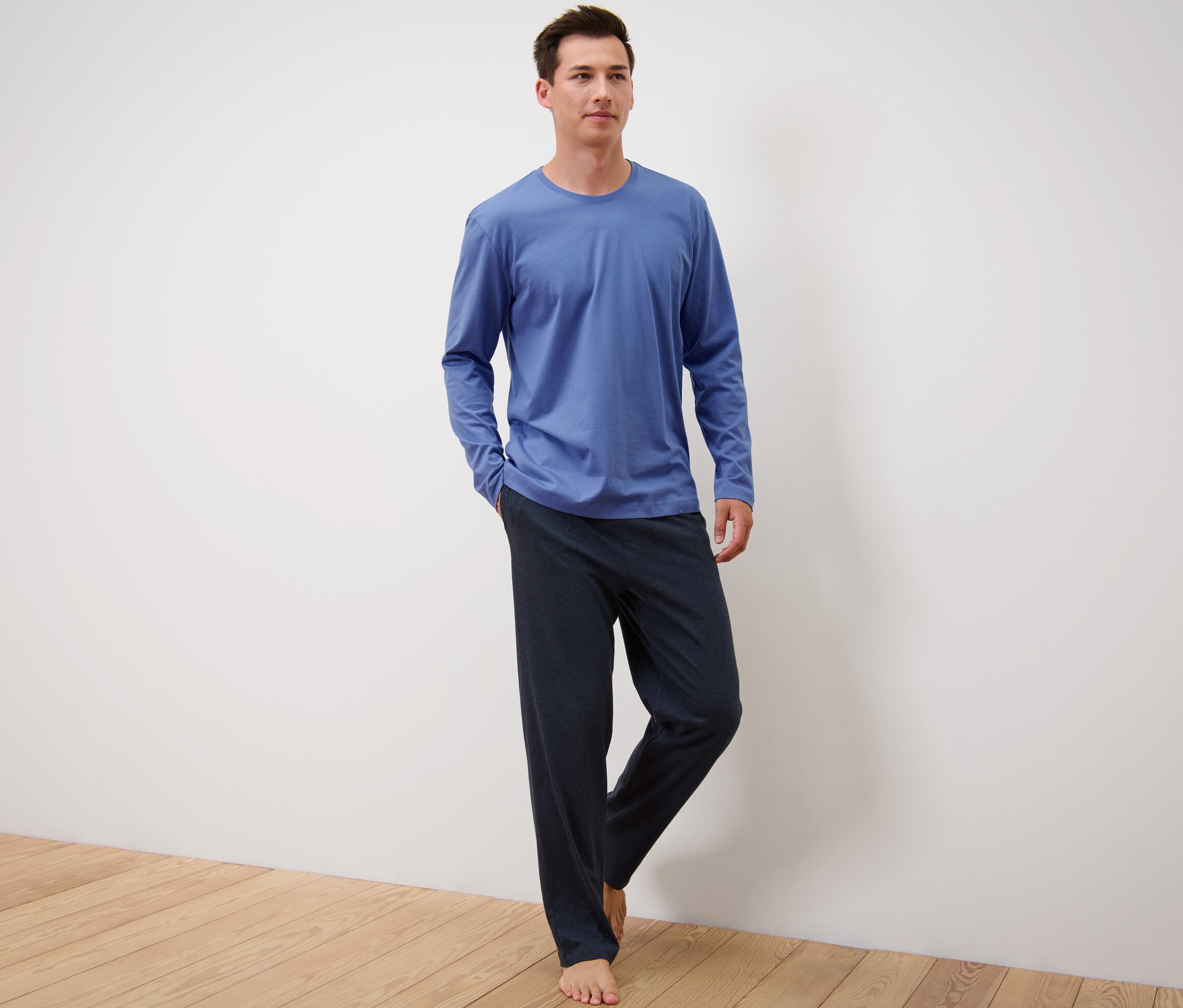 Muž stojí a má na sobě modro-tmavě modré pyžamo.
