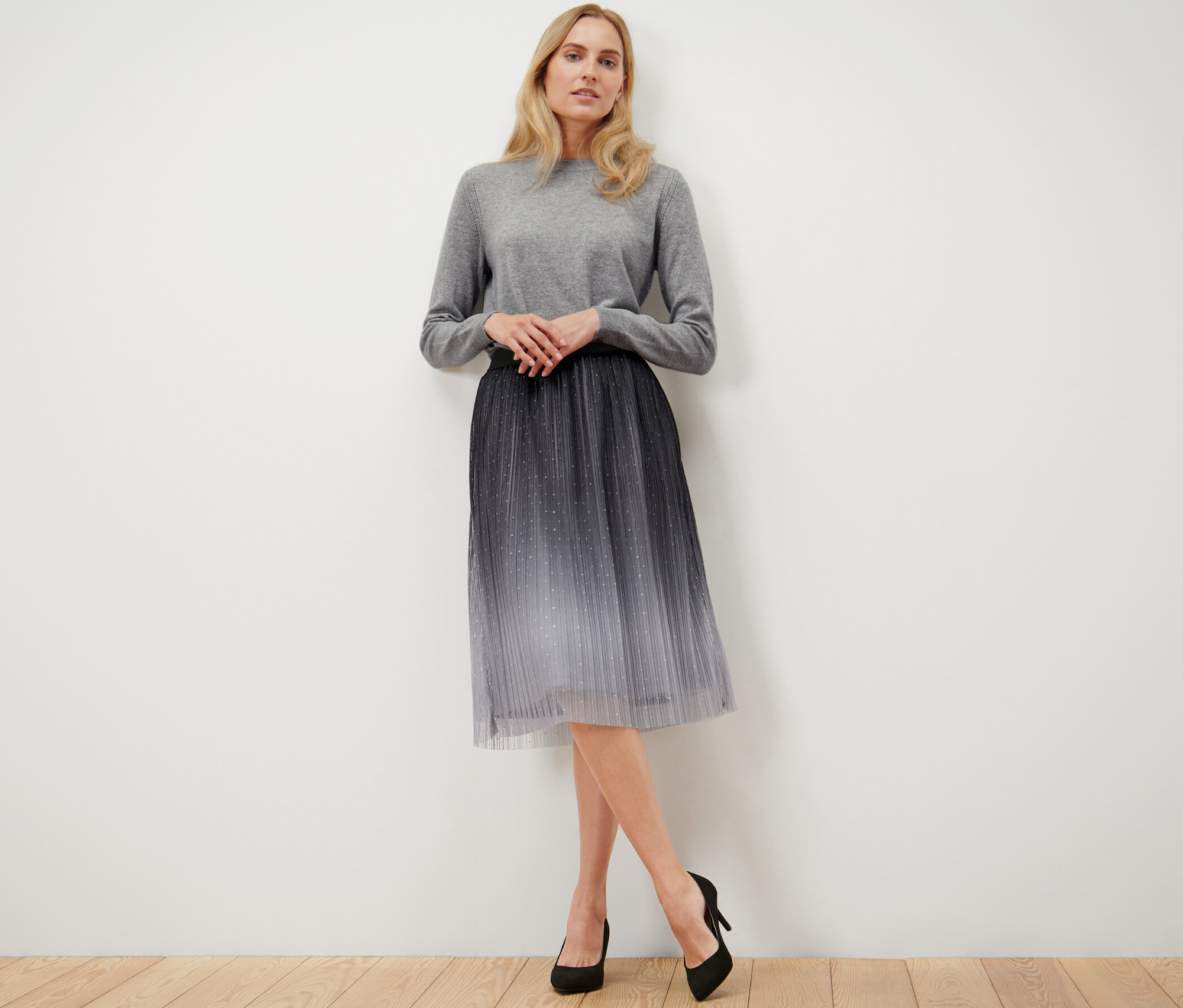 Žena pózuje na sobě plisovanou tylovou sukni s barevným přechodem.