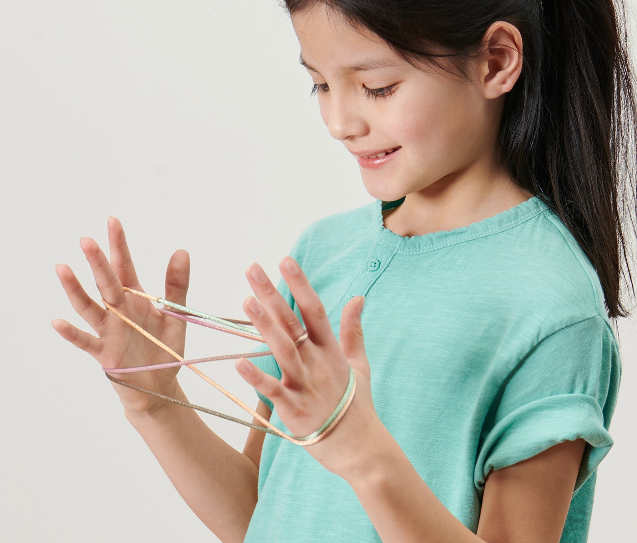 Dívka hraje hru přebírání provázku, sada 2 ks, s provázkem na rukou.