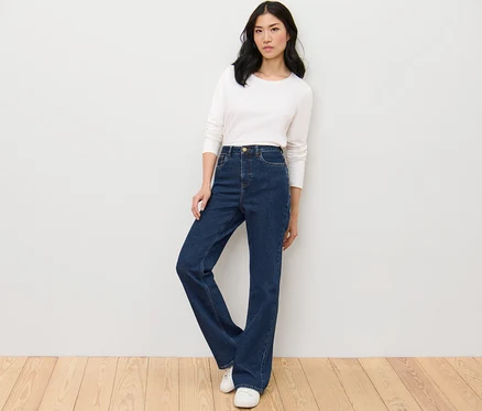 Žena pózuje v bootcut džínách »Lou« a bílém topu.