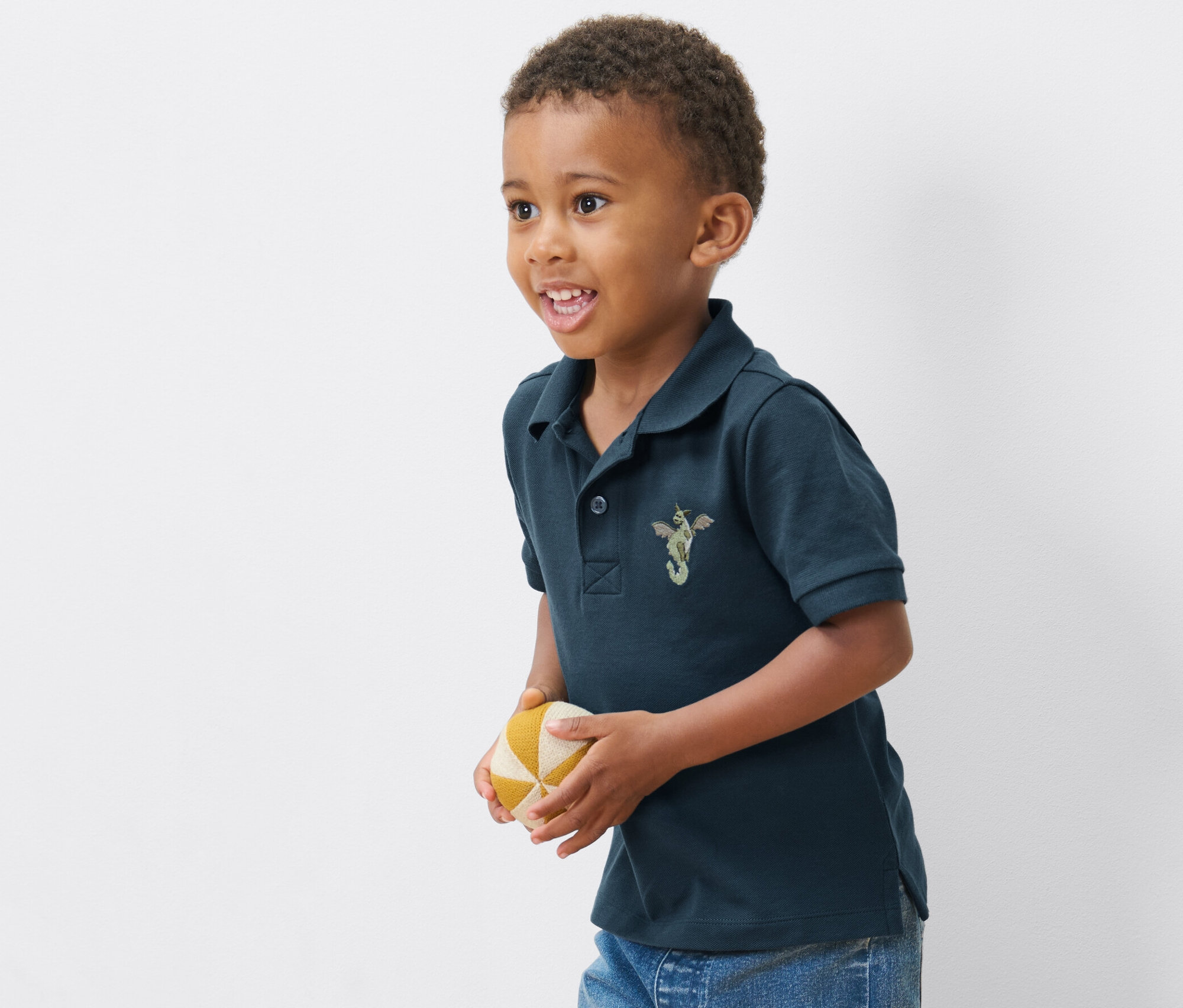 Chlapec v jednom z 2 dětských polokošil z bavlněného piké drží míč.