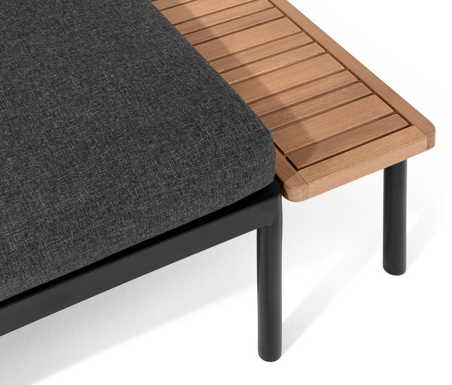 Detail šedé pohovky »Elin« 2 v 1 s područkou z lamelového dřeva a černými kovovými nohami.