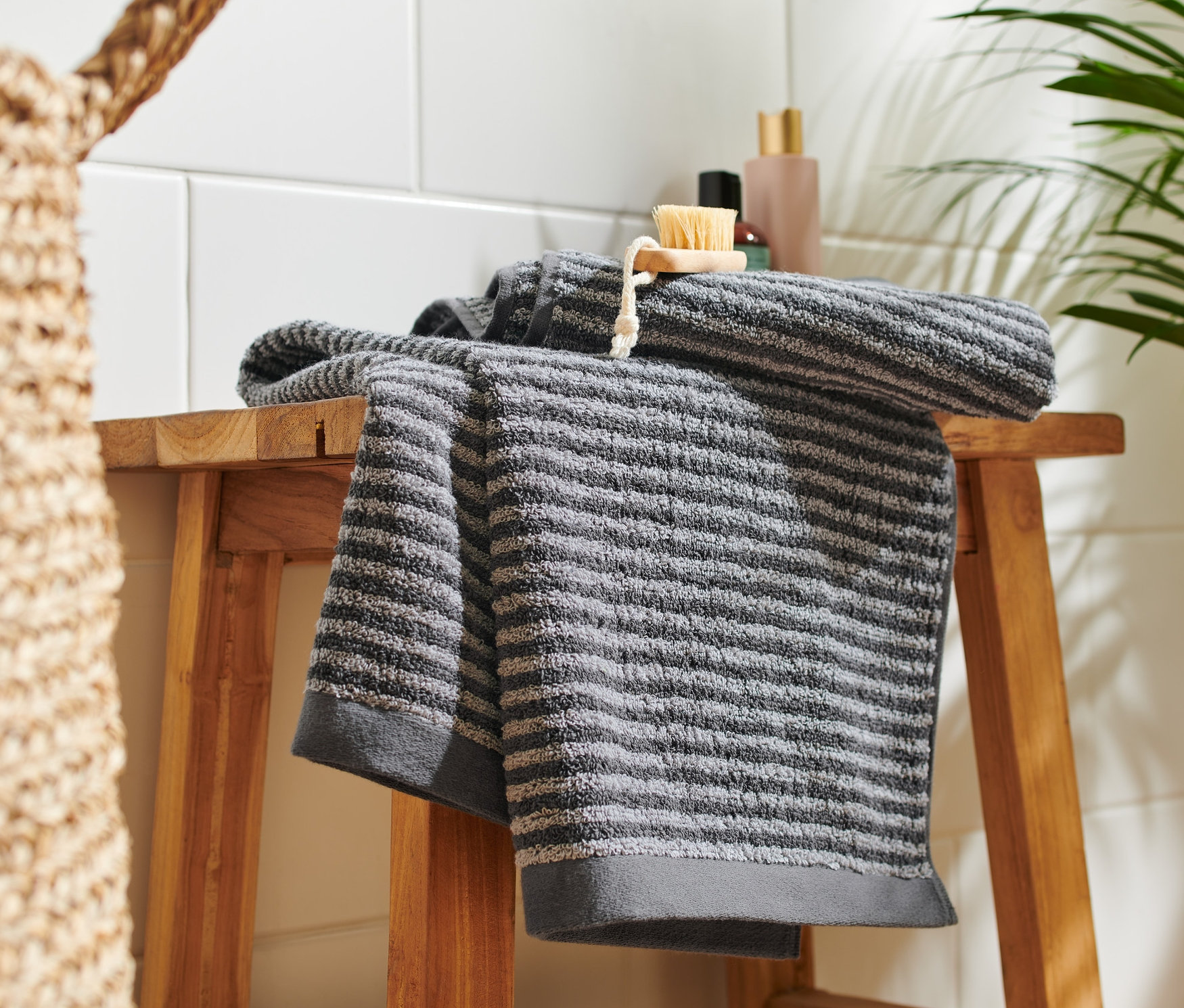 Na dřevěné stoličce leží dva vysoce kvalitní antracitové ručníky.