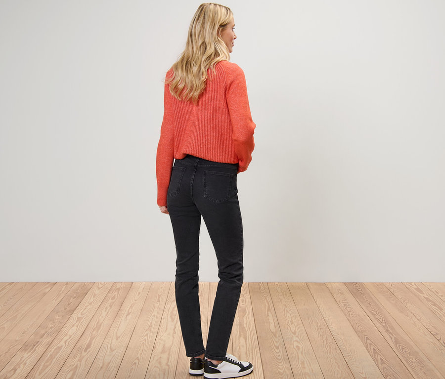 Blondýna pózuje zády, má na sobě oranžový svetr a džíny slim fit »Emma«.