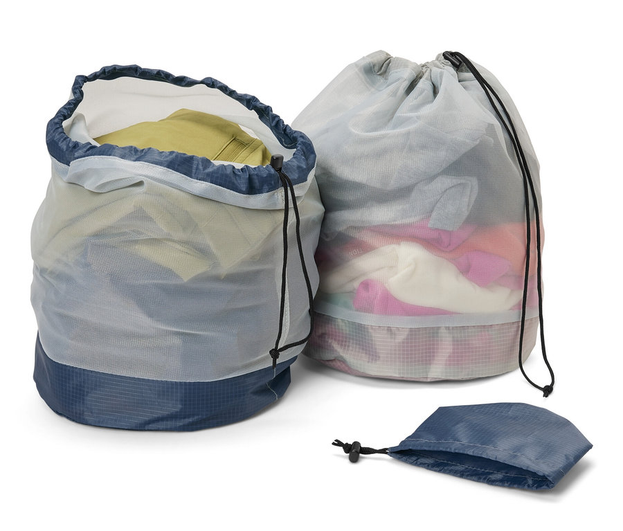Dva outdoorové síťované sáčky, jeden otevřený a plný oblečení, druhý uzavřený, a prázdný sáček.