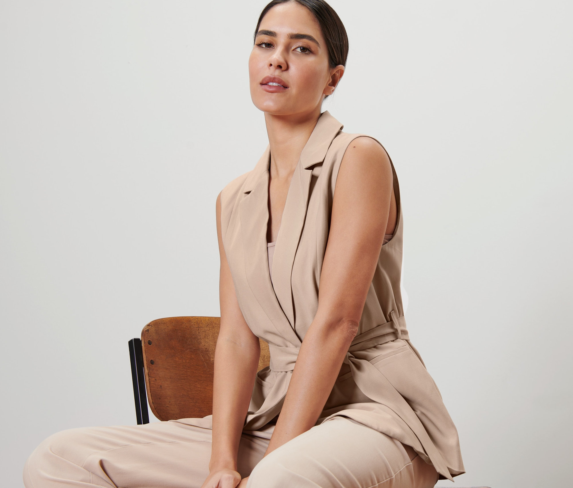 Žena sedí na židli a má na sobě vestu s páskem na zavazování.